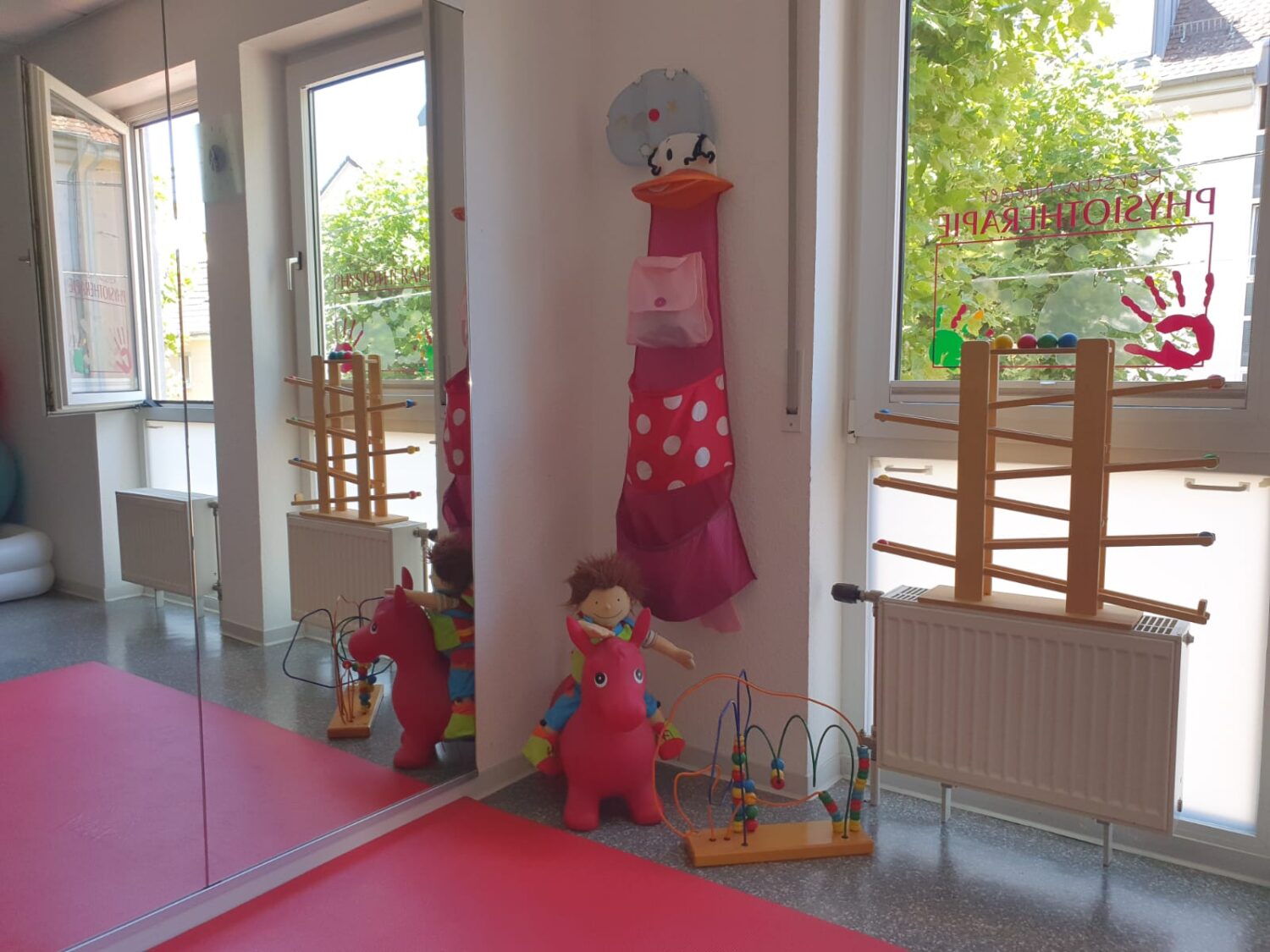 Blick in den freundlich gestalteten Behandlungsraum mit Spielmaterialien für Kinder.